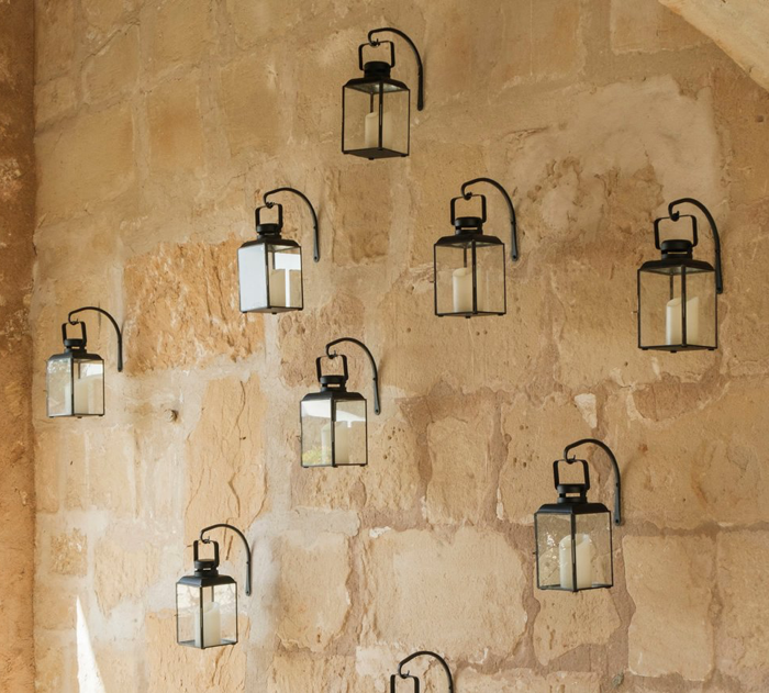stone wall in Mallorca with hanging hurricanes to of glass and black iron