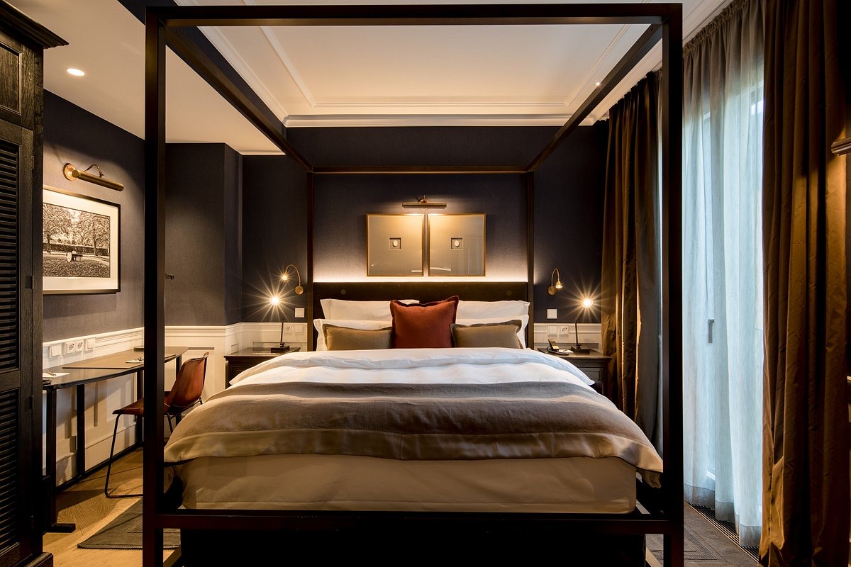 Hotel room with poster bed out of iron, structured wallpaper in dark blue